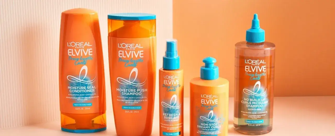 En uppsättning L'Oréal Elvive-produkter för hårvård lockigt hår, inklusive schampo, balsam och leave-in-behandlingar i orange och blå förpackningar.