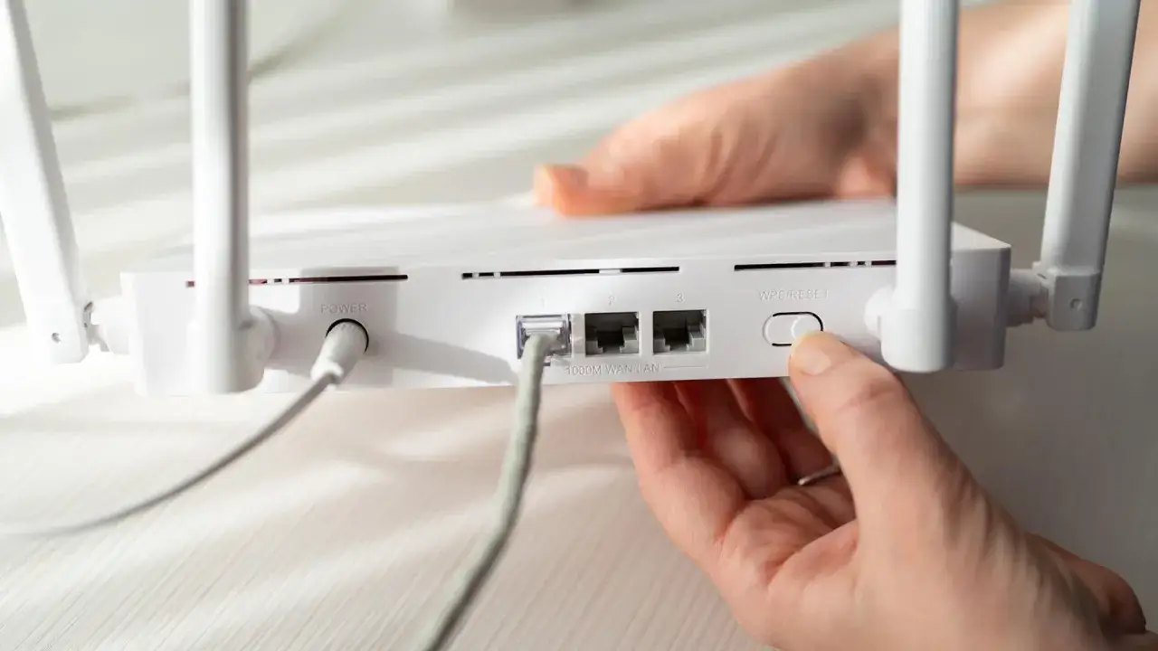 Hände drücken auf den Reset-Knopf des Routers, falls das Router-Passwort vergessen wurde.