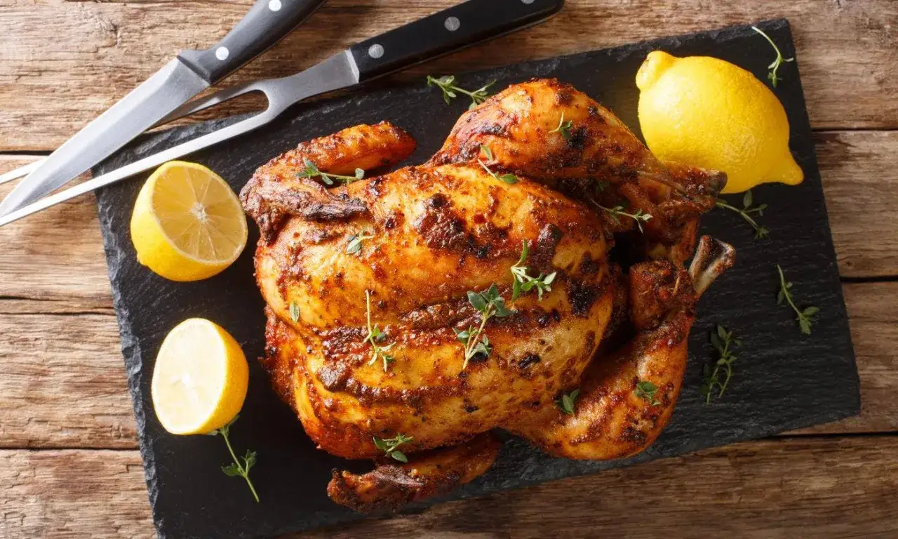 Un jugoso pollo al horno, dorado y crujiente, servido con limones frescos y hierbas. &iexcl;Listo para disfrutar!