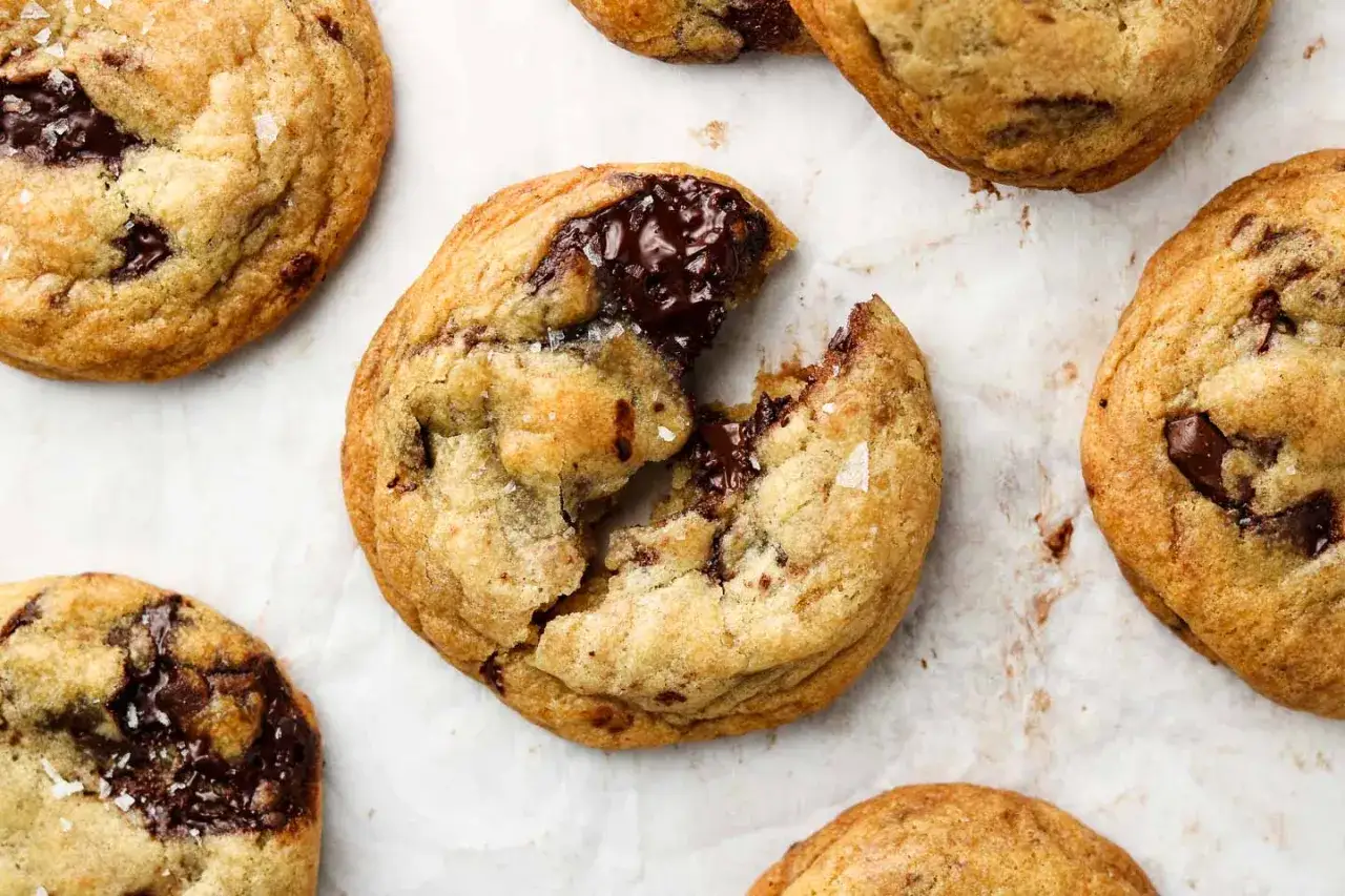 Närbild på flera veganska chocolate chip cookies, en är uppbruten och visar smält choklad.