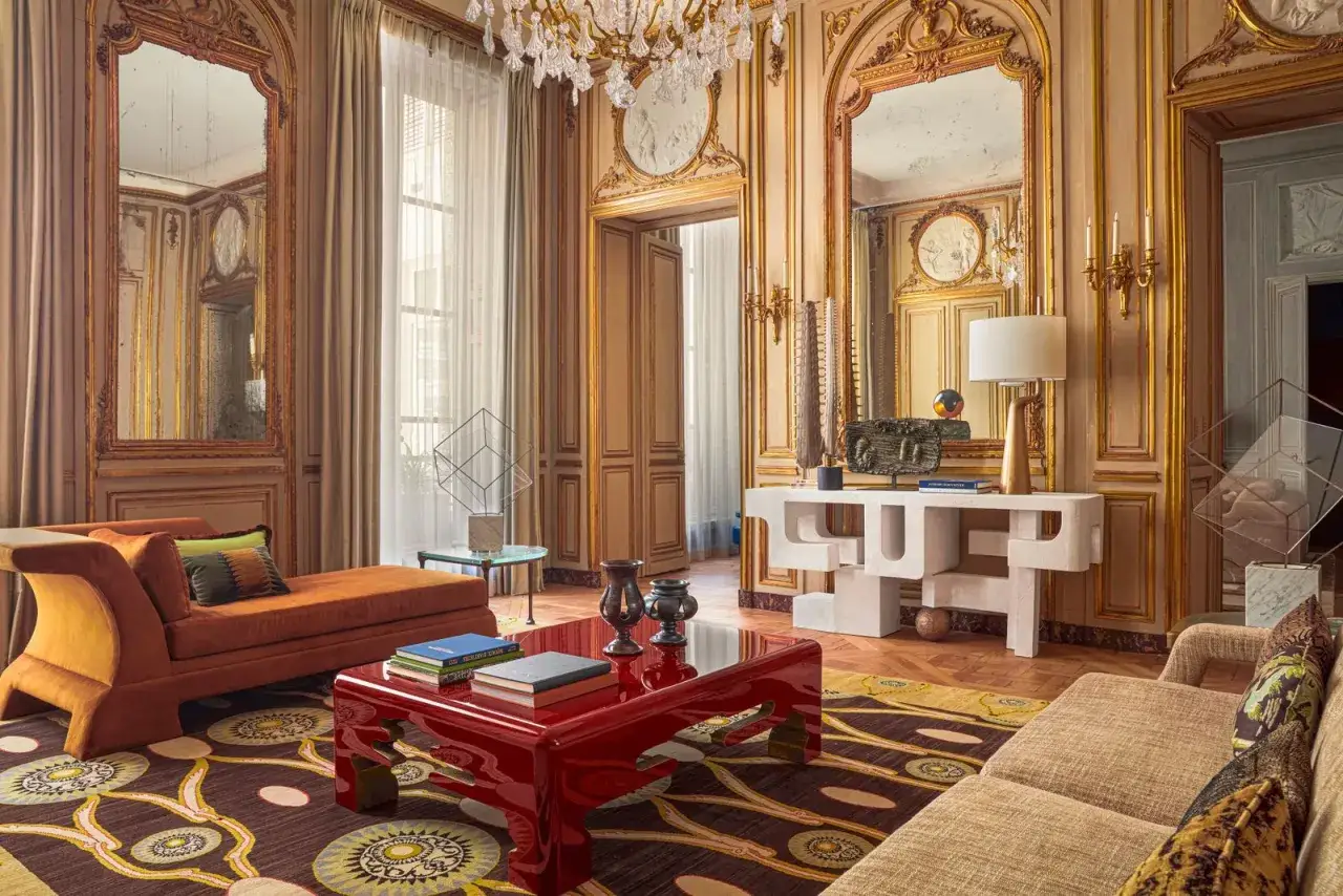 Salon luxueux aux boiseries dorées, mobilier design et tapis aux motifs ethniques. La **couleur chaude** de la peinture des murs et des meubles crée une atmosphère accueillante.