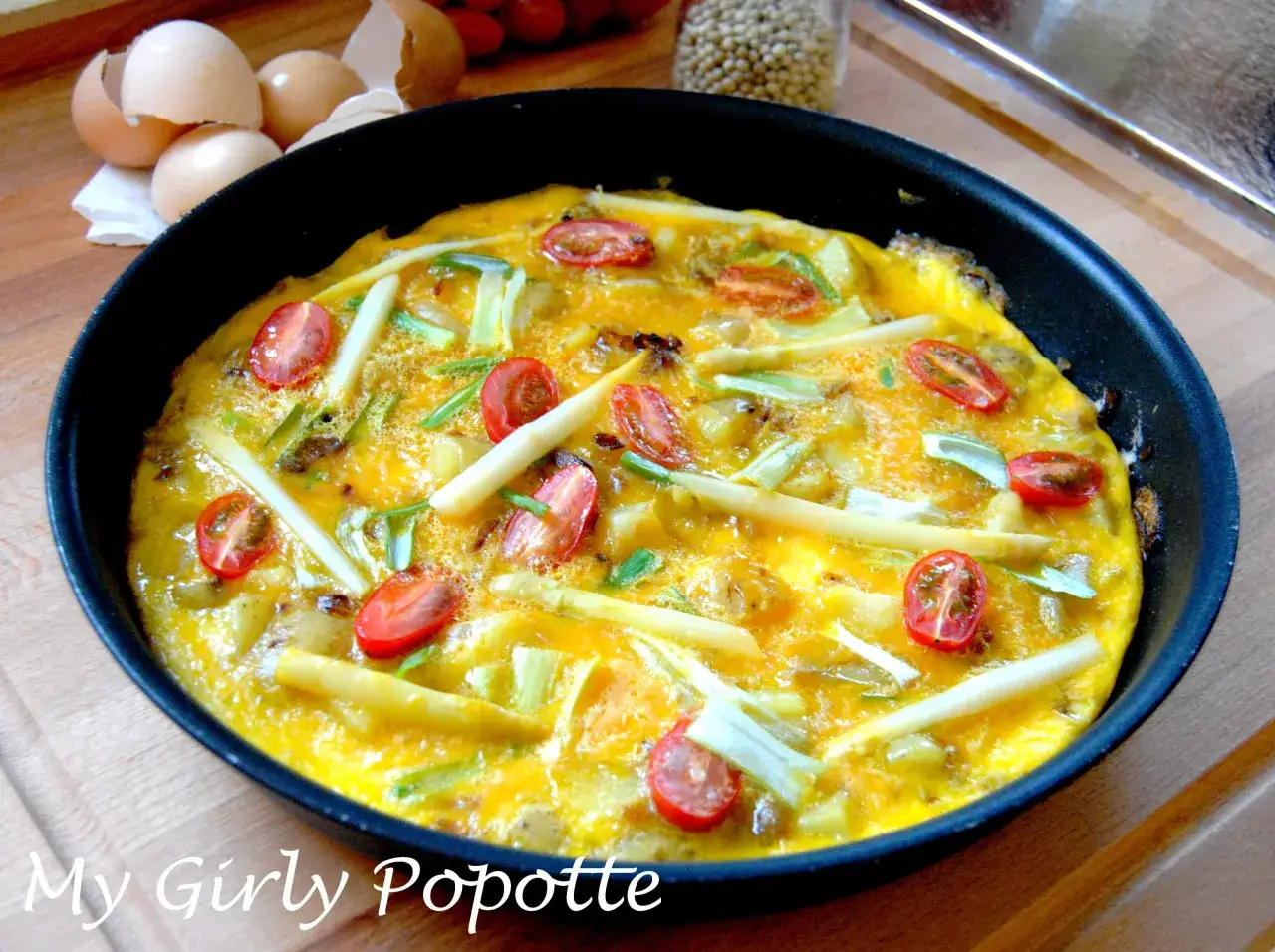 Omelette aux asperges vertes et oignons, garnie de tomates cerises, prête à être dégustée. Une recette simple et savoureuse.