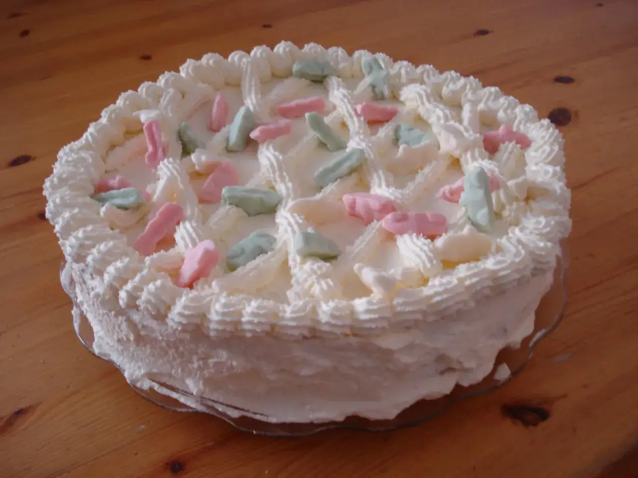 En vit gräddtårta dekorerad med rosa, gröna och vita Ahlgrens bilar. Perfekt för en festlig stund!