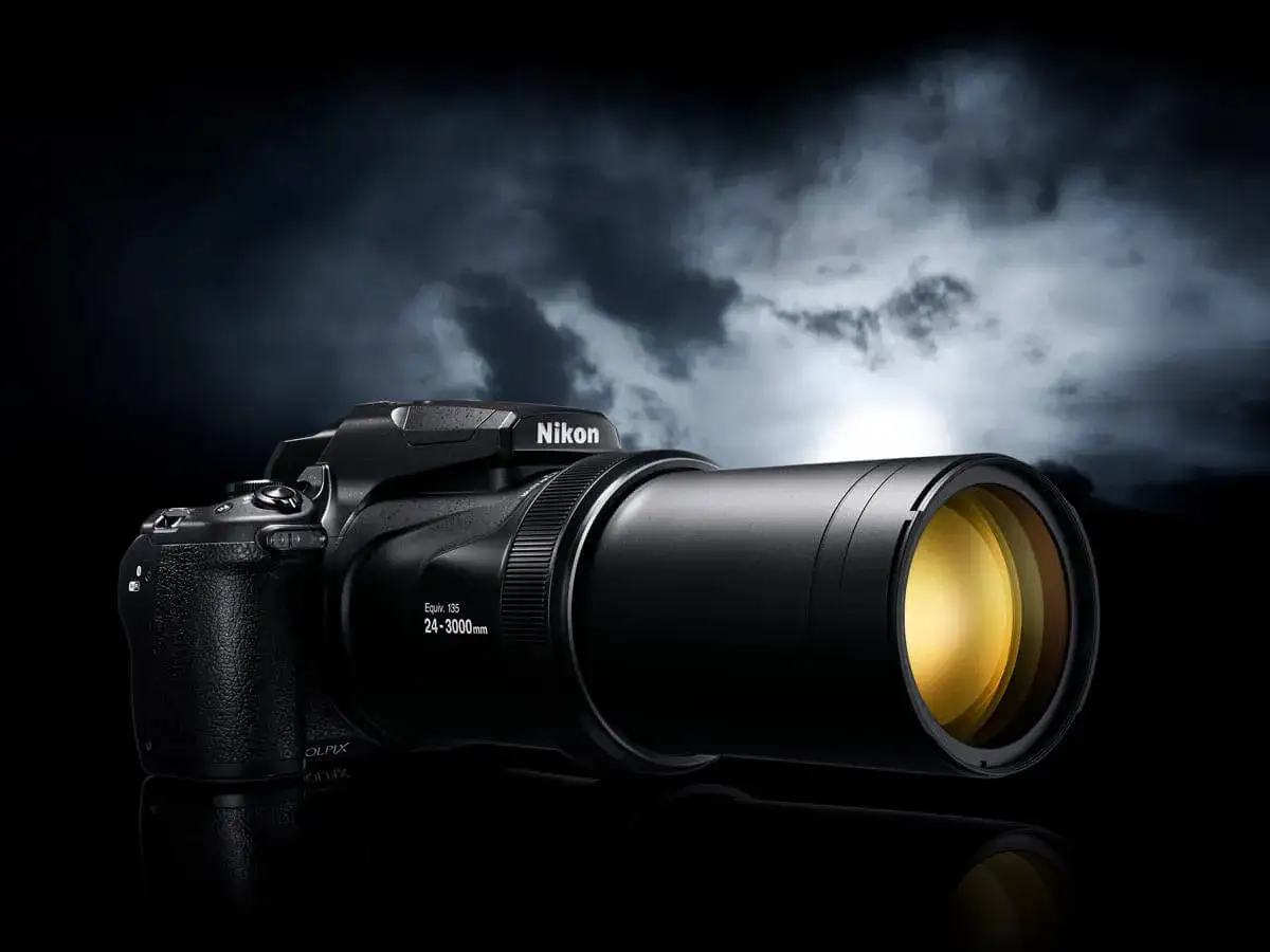 Czarny aparat Nikon Coolpix P1000 z potężnym obiektywem na tle dramatycznego, burzowego nieba.