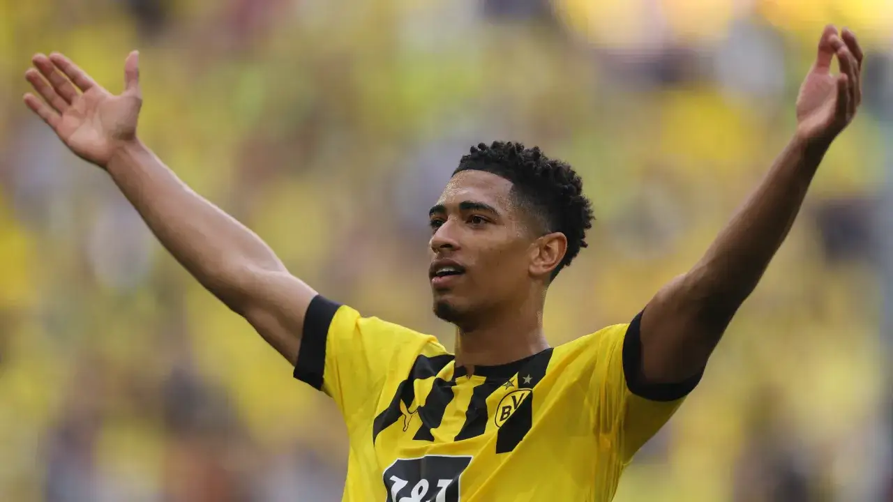 Jude Bellingham celebra un gol con los brazos en alto, vistiendo la camiseta amarilla del Dortmund.