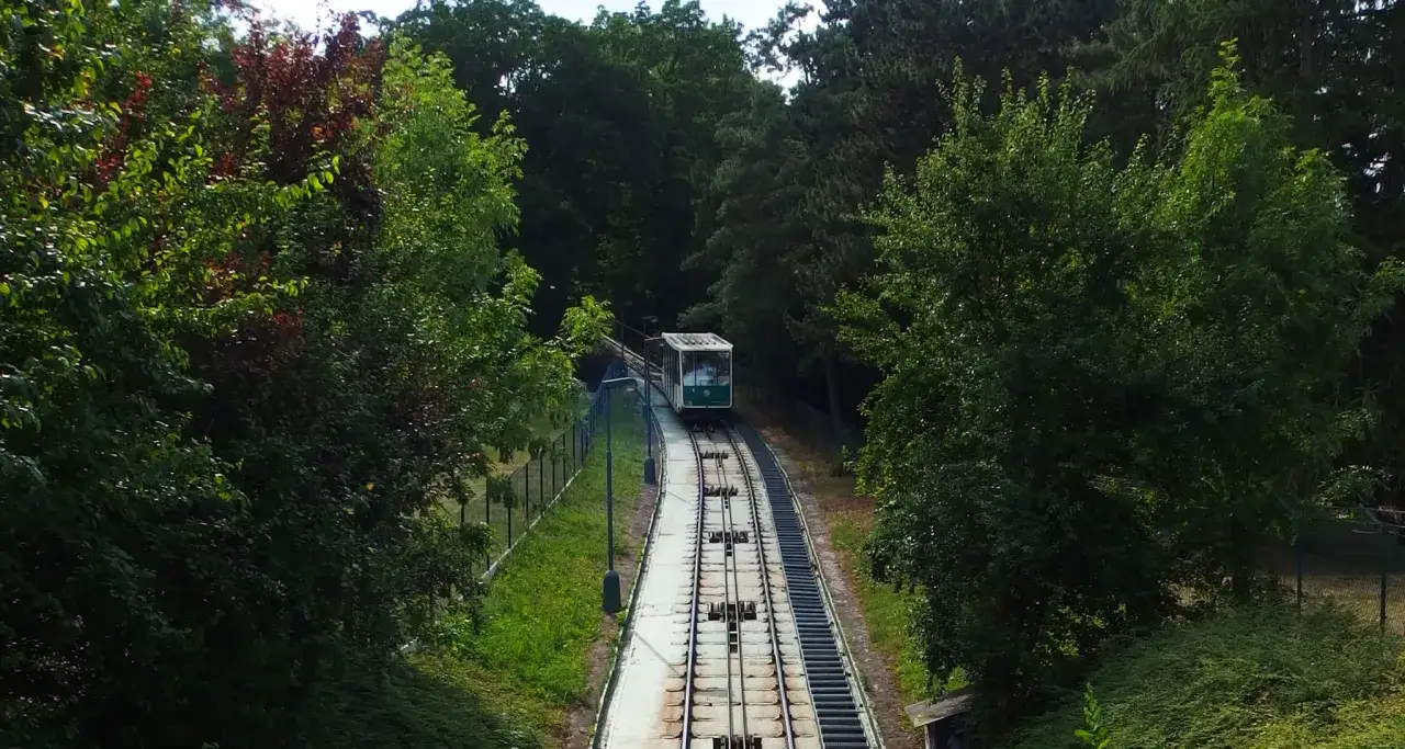 Zielona kolejka linowa Praga wspina się po stromym zboczu wśród bujnej zieleni.