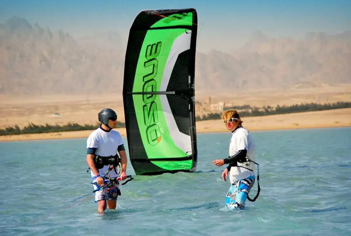 Dwóch kitesurferów w wodzie, piękna pogoda w Egipcie, Marsa Alam. Góry w tle.