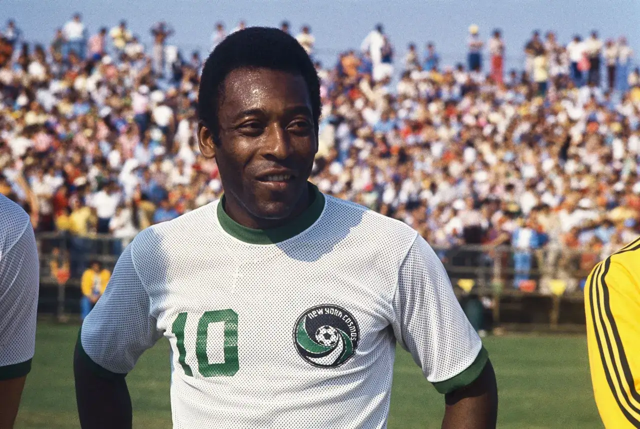 Piłkarz Pelé w koszulce New York Cosmos, jednego z klubów, w jakich grał. Tłum kibiców na trybunach.