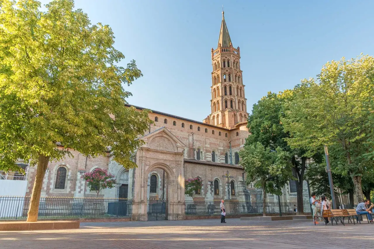 La basilique Saint-Sernin, un incontournable pour savoir que faire &agrave; Toulouse. L'architecture romane et son clocher octogonal dominent la place.