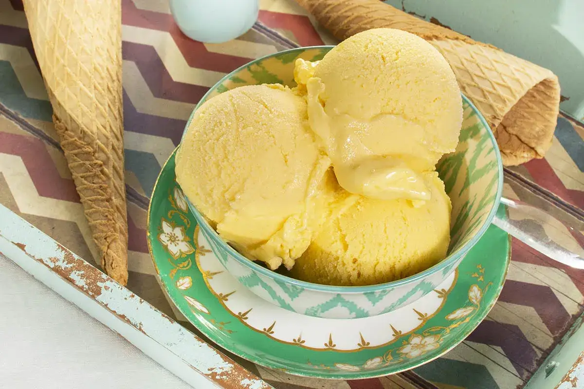 Delicioso helado de mango en un cuenco decorado, listo para ser servido en conos crujientes.