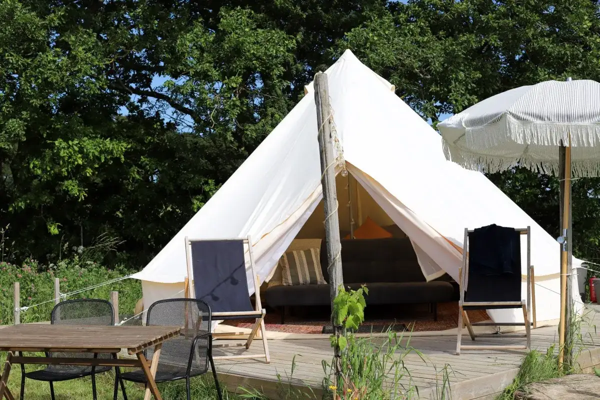En vit glampingtält i Mölle med en bekväm soffa och parasoll. Perfekt för en avkopplande vistelse.