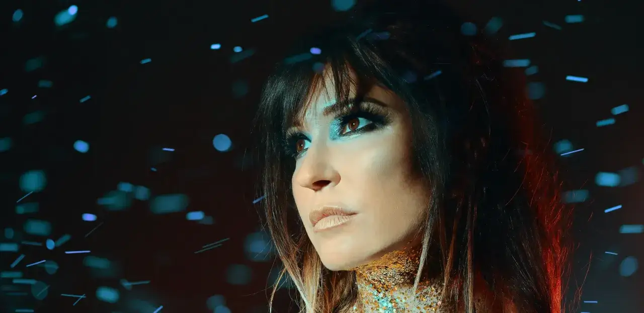Une femme au maquillage éclatant, parée de paillettes dorées, semble prête à enflammer la scène en tant que dj rap.