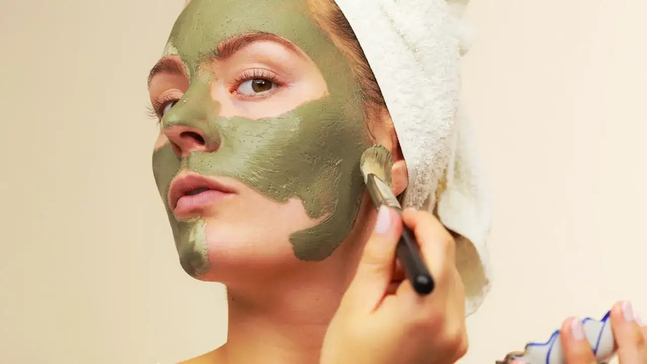 Mujer aplicándose mascarilla de arcilla verde, aprovechando sus propiedades purificantes para una piel radiante.