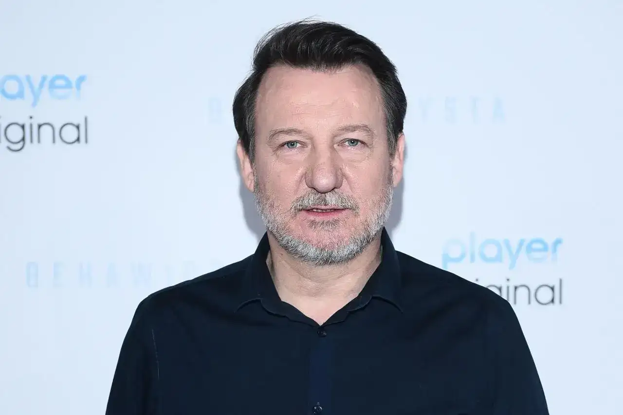 Robert Więckiewicz, znany z wielu filmów, seriali i programów, na tle napisu