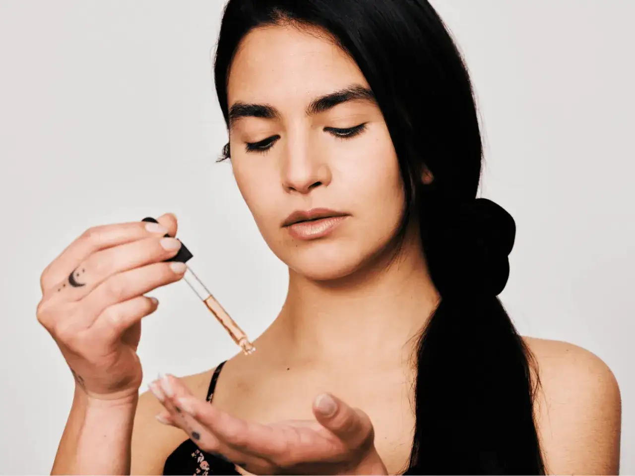 Descubre la vitamina E para que sirve en el cabello. Una mujer aplica un sérum con gotero en su mano, buscando un cabello radiante.
