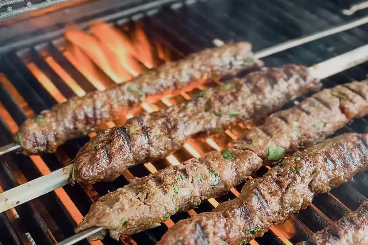 Saftige Hackfleischspie&szlig;e mit Kr&auml;utern garen &uuml;ber Flammen. Ein Beispiel f&uuml;r raffinierte Hackfleisch Rezepte, die auf dem Grill zubereitet werden.