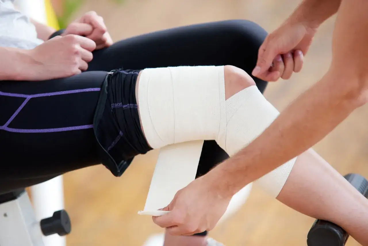 Aplicaci&oacute;n del m&eacute;todo RICE para tratar una lesi&oacute;n de rodilla, vendando la zona afectada para reducir la inflamaci&oacute;n y el dolor.
