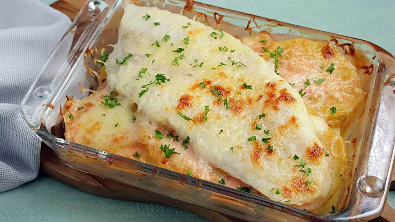 Ein köstlicher Fischauflauf mit Kartoffeln und geschmolzenem Käse, garniert mit Petersilie. Perfekt für ein einfaches Fischauflauf Rezept.