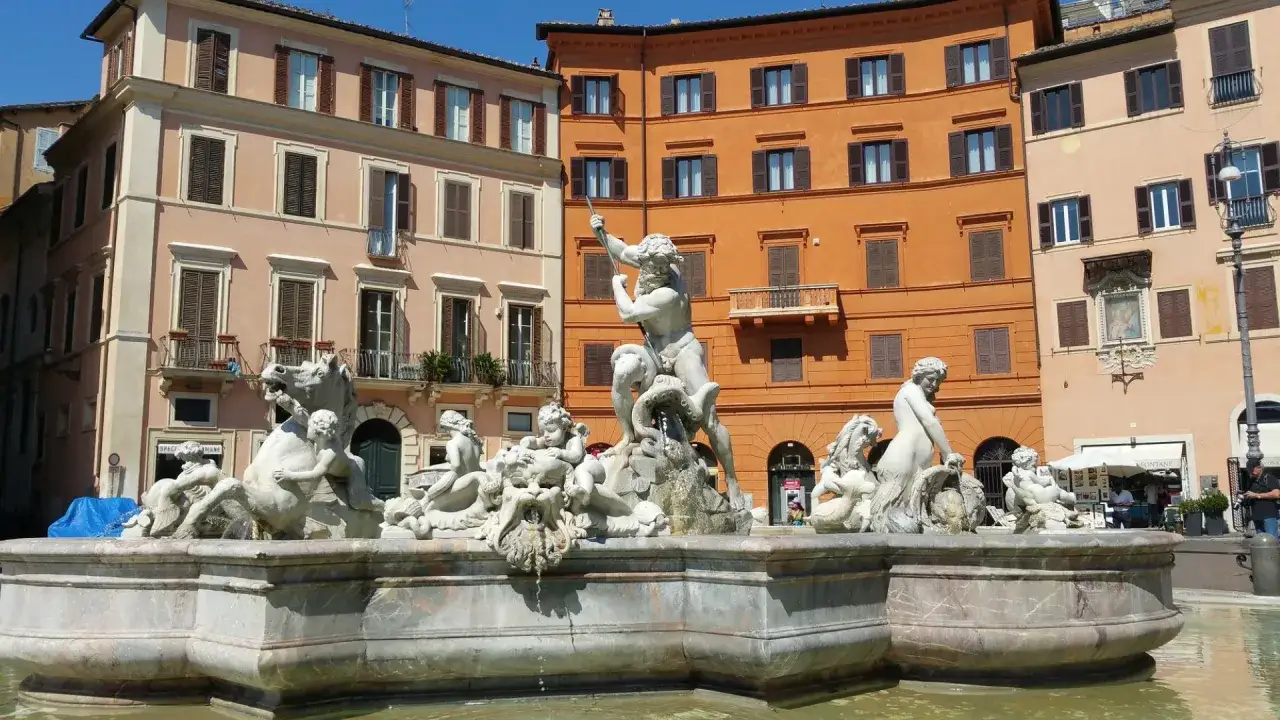 Fontana del Moro a Piazza Navona, una curiosità artistica con statue di marmo e palazzi colorati sullo sfondo.