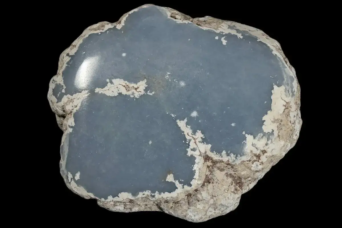Ein glatter, blauer Angelit Stein mit rauer, weißer Kruste.