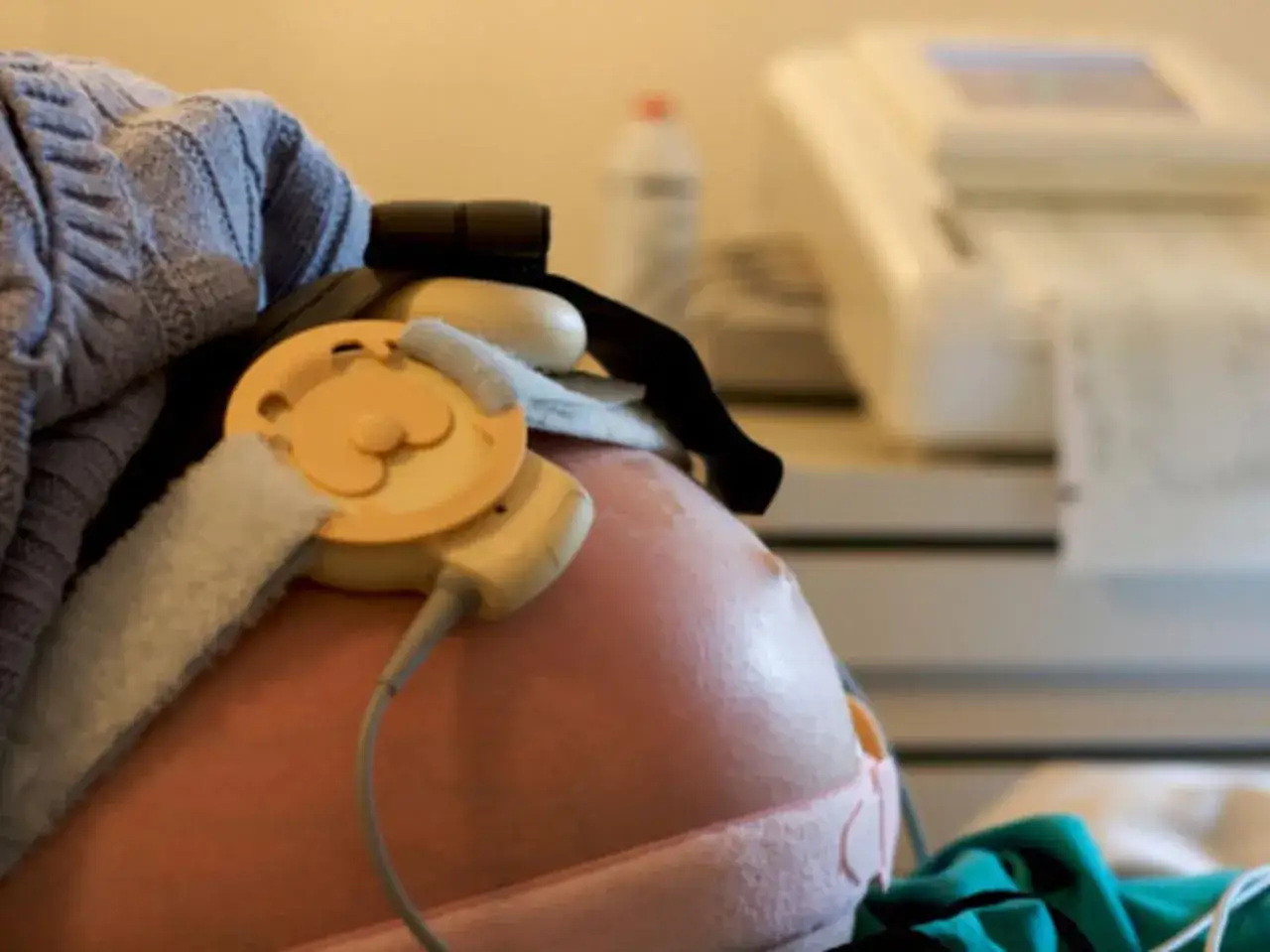 Monitor KTG na brzuchu ciężarnej, badanie w jednym z trymestrów ciąży.