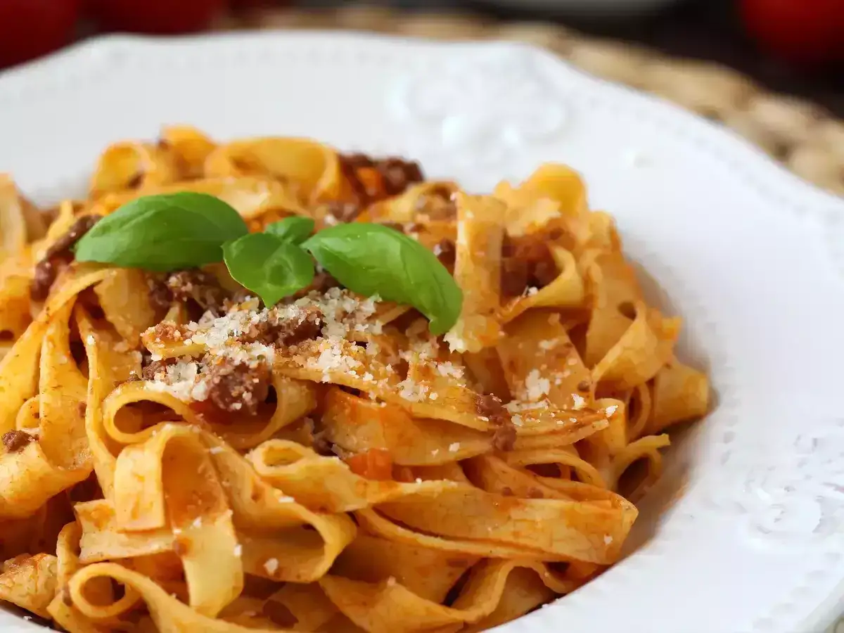 Pyszne tagliatelle z sosem bolognese, posypane parmezanem i udekorowane bazylią. Idealny spaghetti bolognese przepis oryginalny.