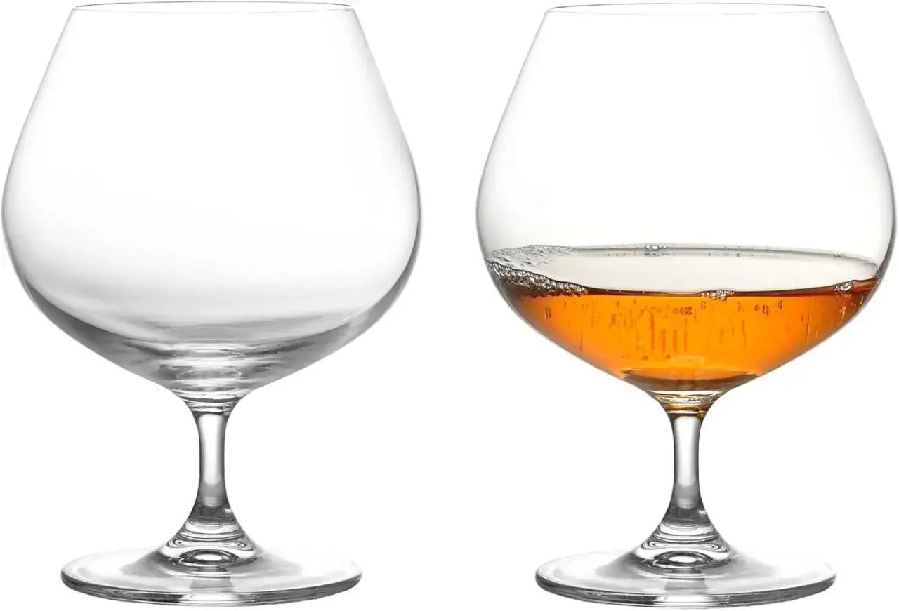 Deux verres &agrave; pied, l'un vide, l'autre rempli d'un armagnac digestif ambr&eacute; aux bulles fines.