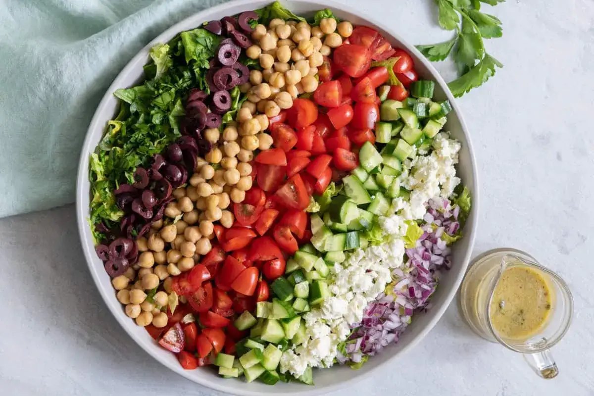 Insalata colorata con ceci, pomodori, cetrioli, cipolla rossa, olive, formaggio e condimento. Ottima per un pasto leggero, con poche primosale calorie.