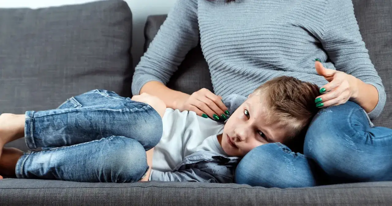 Chłopiec przytula się do mamy, szukając pocieszenia. Mama delikatnie głaszcze go po głowie, wspierając w trudnych chwilach, gdy szukamy domowe sposoby na owsika u dzieci.