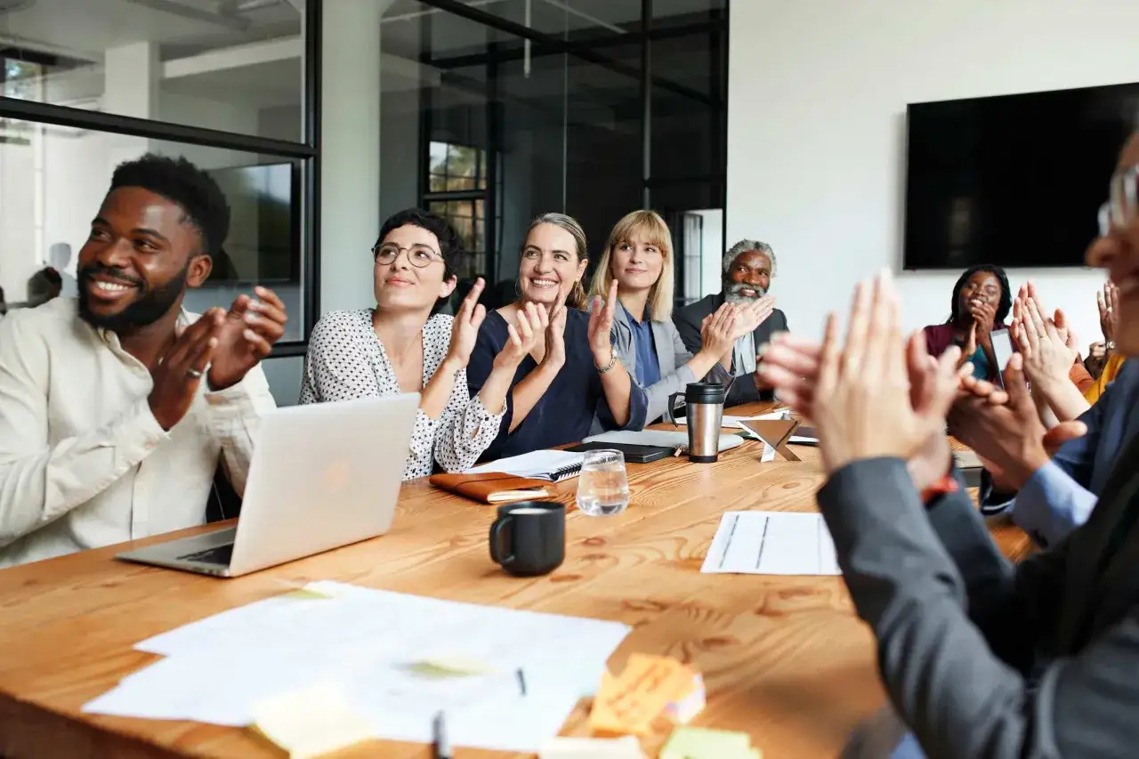 A diverse team applauds, celebrating success. This scene embodies resonant leadership, where shared achievement fosters a positive and collaborative atmosphere.