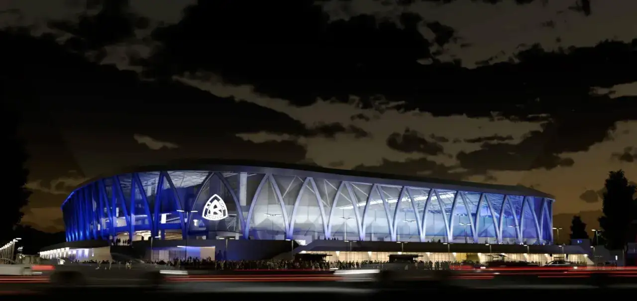 Nowoczesny, oświetlony na niebiesko nowy stadion Ruchu Chorzów nocą, z widocznym herbem klubu.