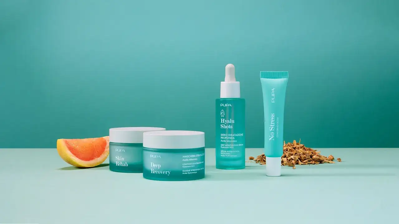 Prodotti Pupa con acido ialuronico per pelle grassa: siero, maschera e contorno occhi. Una fetta di pompelmo e corteccia completano la scena.