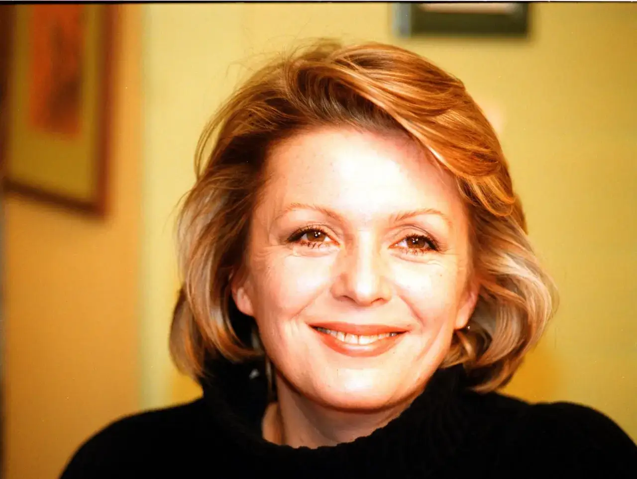 Uśmiechnięta Gabriela Kownacka z rudawymi włosami i w czarnym golfie.