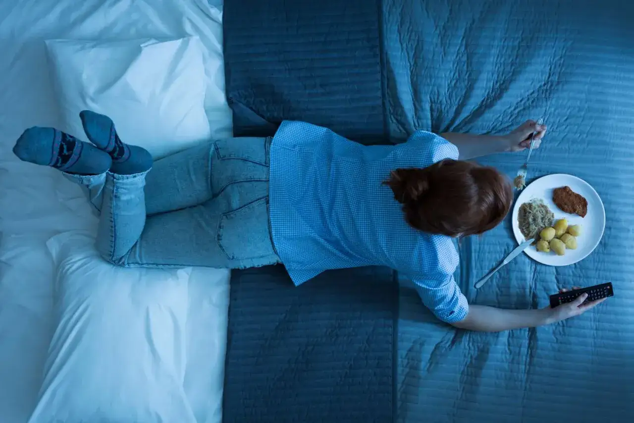 A person eats a meal in bed, holding a remote. Is it bad to go to sleep after eating?
