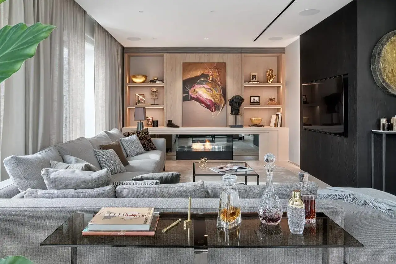 Nowoczesny salon w stylu nowojorskim. Szara sofa, kominek, dzieło sztuki i dekoracje tworzą elegancką przestrzeń.