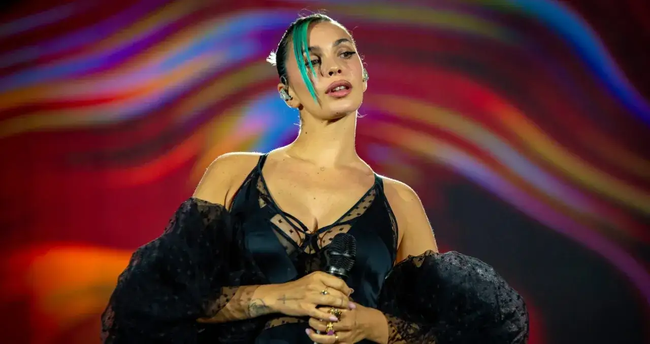 La cantante, con capelli verdi e un abito nero, sembra una rose villain sul palco.