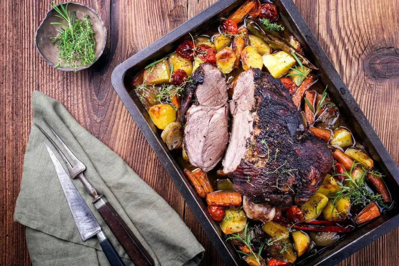 Poitrine d'agneau rôtie avec légumes colorés dans un plat, prête à être dégustée.