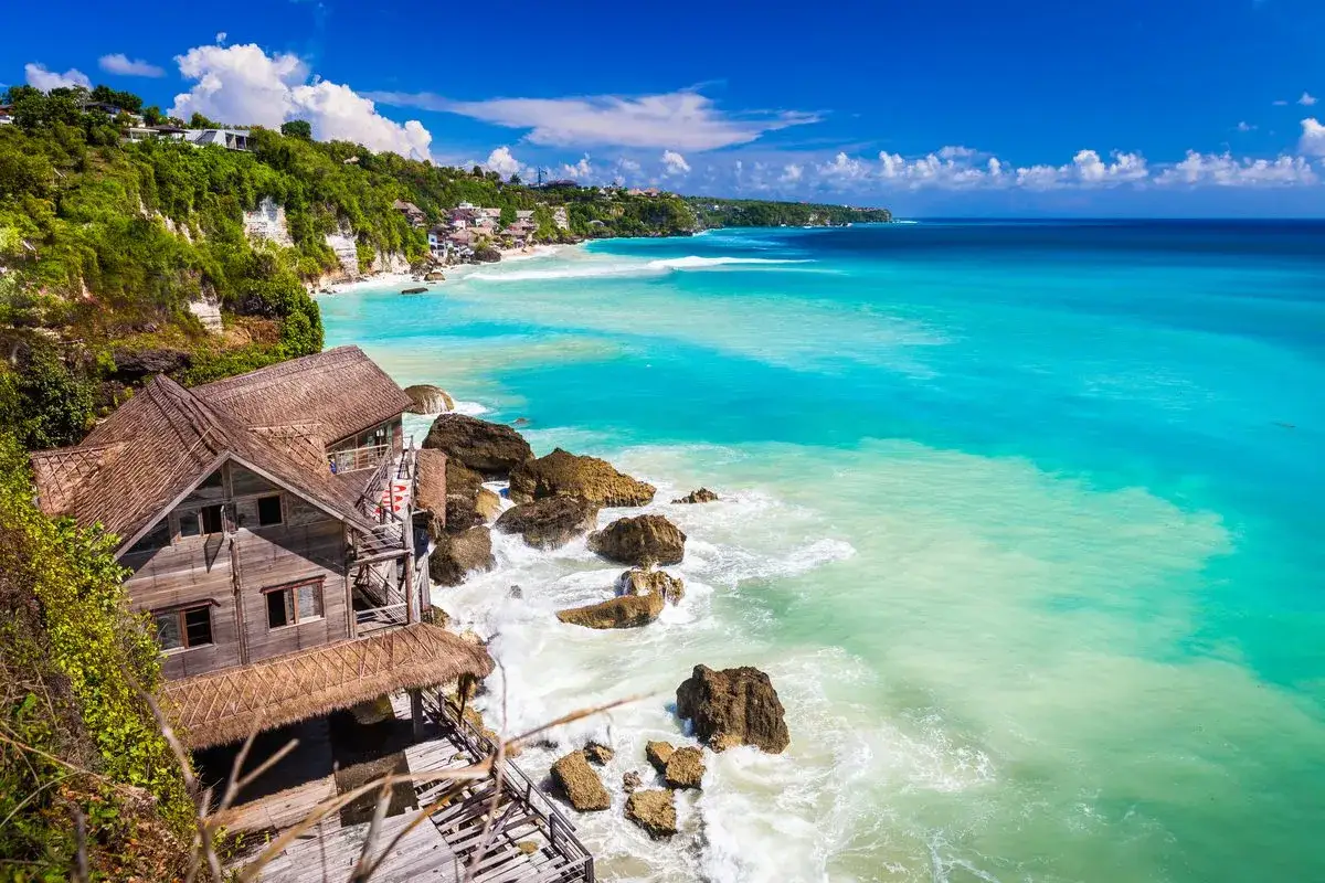 Piękna plaża na Bali z drewnianymi domkami. Zastanawiasz się, ile trwa lot na Bali z Polski? To długa podróż, ale widoki są tego warte!