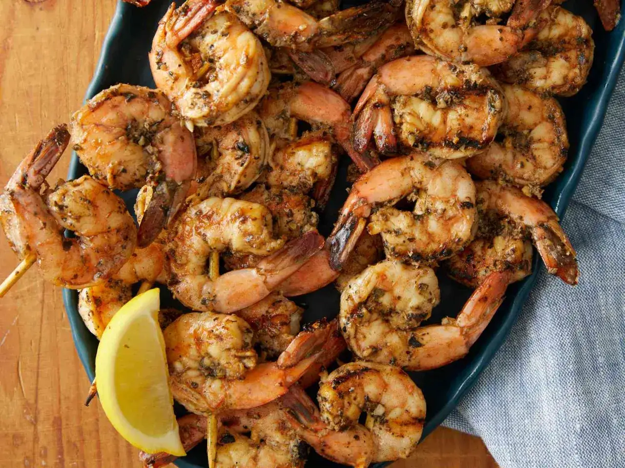 Gambas grillées sur brochettes, assaisonnées et servies avec un quartier de citron. Une délicieuse recette de gambas.