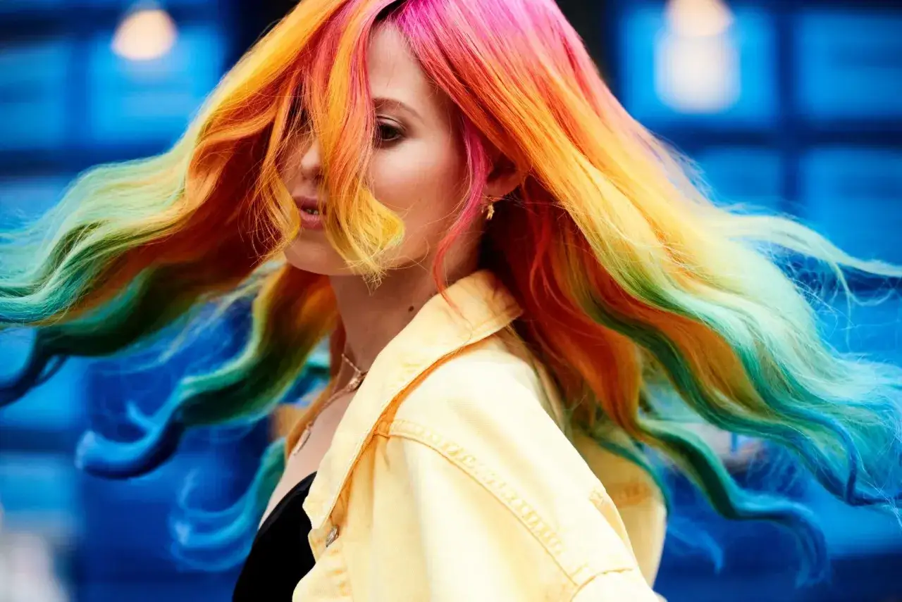 Frauenkopf mit lebendiger Keune Haarfarbe im Regenbogenstil, die sich im Wind bewegt.