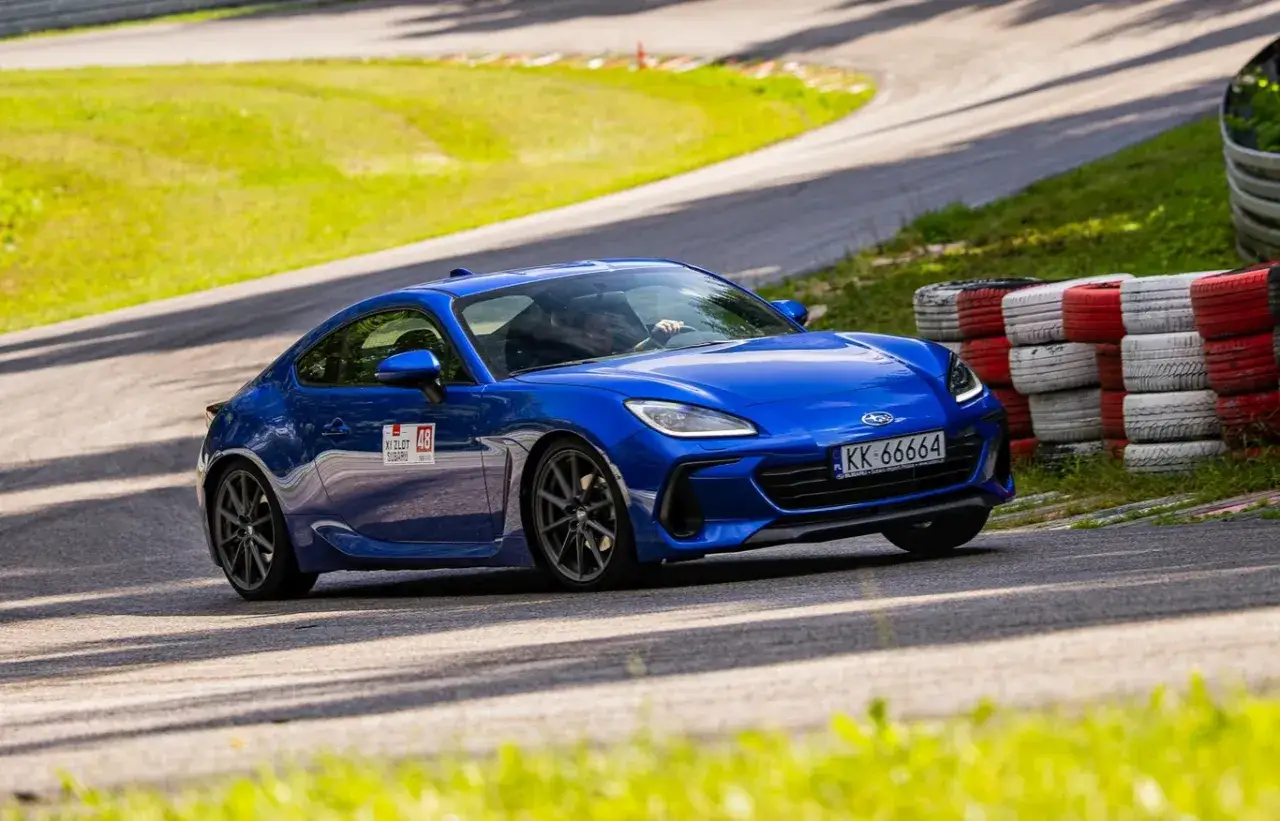 Niebieski Subaru BRZ na torze wyścigowym, z oponami w tle.