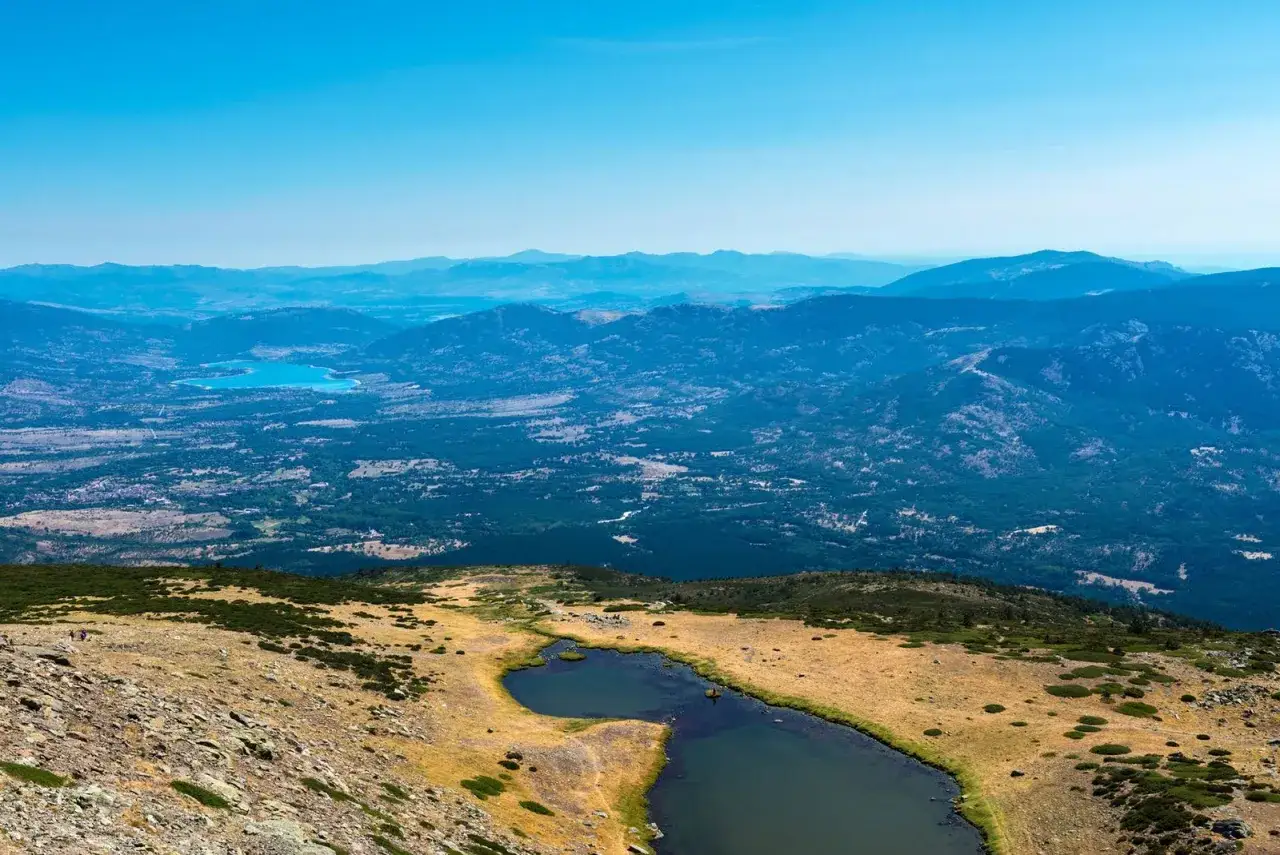 Vistas desde el mirador de la gitana: lagunas, bosques y montañas azules bajo un cielo despejado.