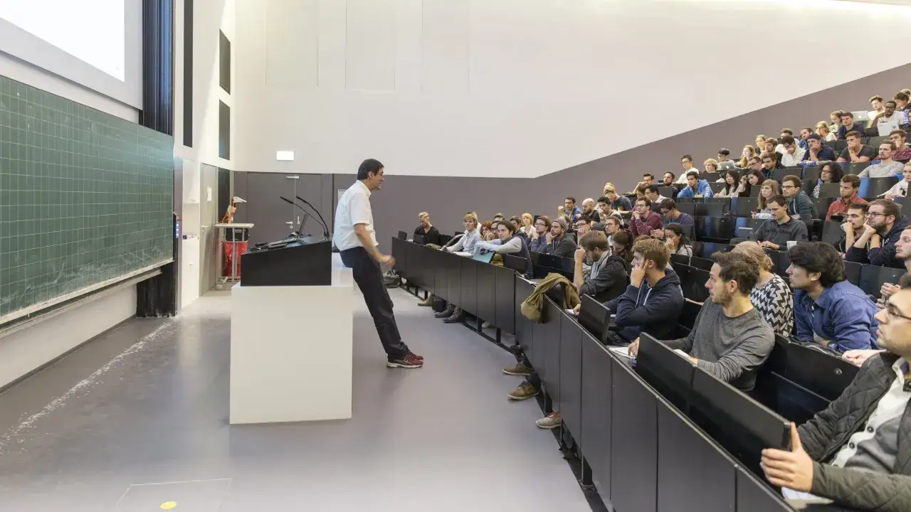 Dozent erklärt vor Studierenden im Hörsaal. Die Frage nach Ausbildung vs Studium beschäftigt viele junge Menschen.