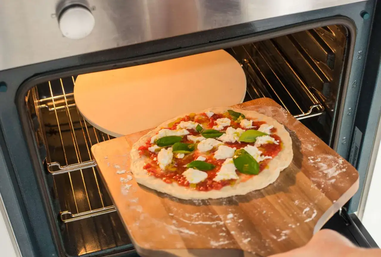 En hemlagad pizza med tomatsås, mozzarella och basilika är redo att bakas i ugnen. Ett perfekt pizza recept för hemmakockar.