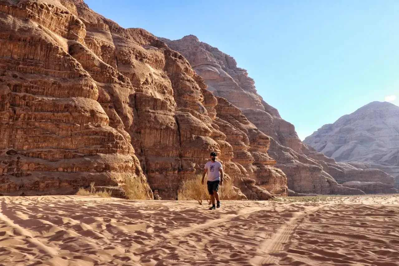 Mężczyzna spaceruje po piaszczystej dolinie Wadi Rum. Idealny czas, kiedy najlepiej lecieć do Jordanii, to wiosna lub jesień.
