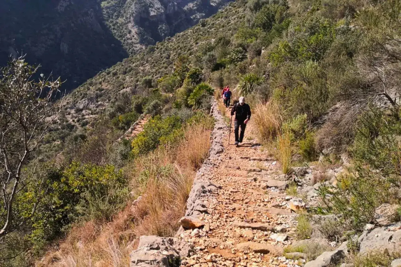 Senderistas ascienden por un camino pedregoso, la