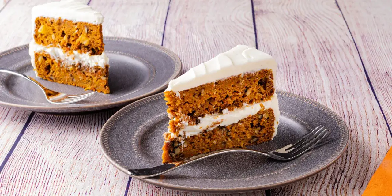 Dos porciones de pastel de zanahoria con glaseado blanco cremoso, listas para disfrutar.