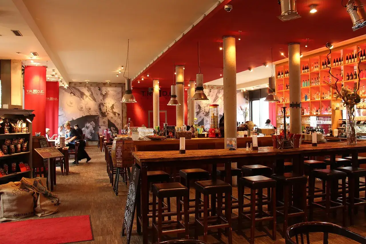 Gem&uuml;tliche Bar im T.R.U.D.E. Hamburg mit Holztresen, Barhockern und Regalen voller Flaschen.