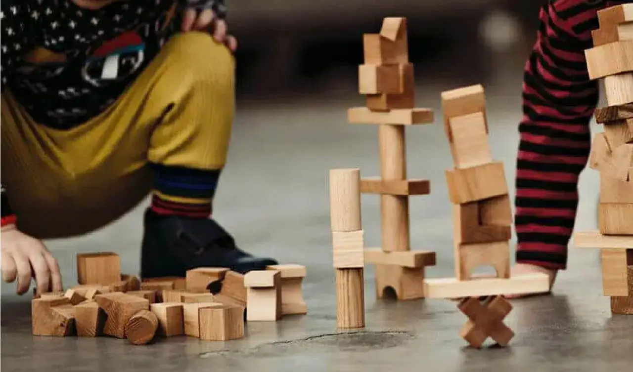 Bambini giocano con blocchi di legno, creando torri e forme. Ecco cosa costruire con le costruzioni: fantasia e creatività senza limiti.