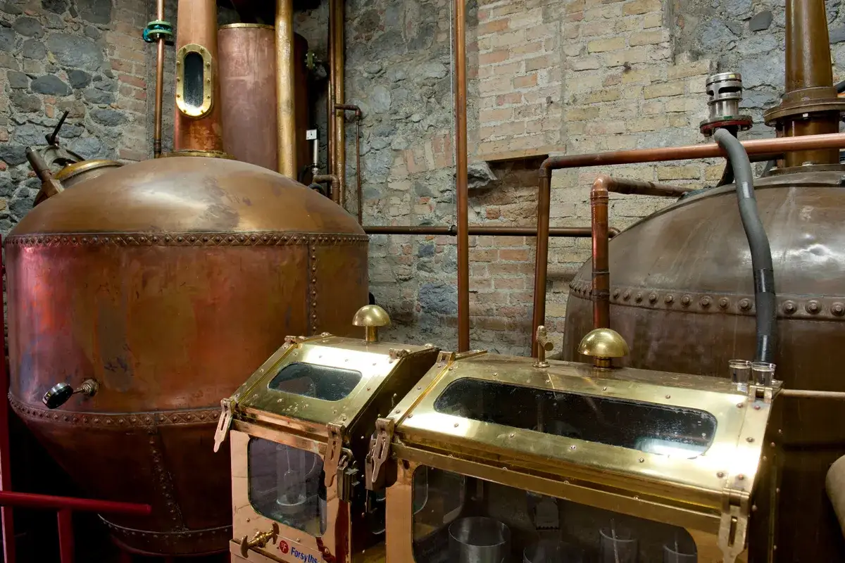 Kupferne Brennblasen und Messing-Ablaufk&auml;sten in einer Destillerie, bereit f&uuml;r das Whisky brennen.
